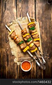 Shish kebab of meat and vegetables with the sauce.On wooden background.. Shish kebab of meat and vegetables with the sauce.