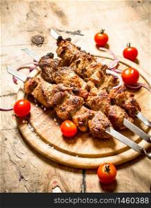 Shish kebab on skewers with tomato. On a wooden table.. Shish kebab on skewers with tomato.
