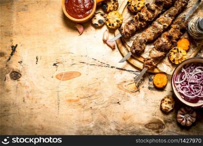Shish kebab with salad, vegetables and beer. On a wooden table.. Shish kebab with salad, vegetables and beer.