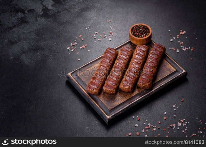 Shish kebab with vegetables on black concrete background. Grilled kebab with spices and herbs on a dark concrete background