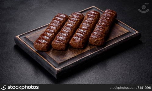 Shish kebab with vegetables on black concrete background. Grilled kebab with spices and herbs on a dark concrete background