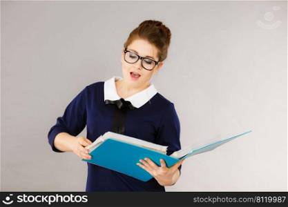 Shocked accountant business woman looking at documents in binder seeing something surprising. Shocked business woman looking at documents