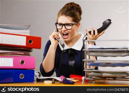 Shocked accountant business woman sitting working at desk full off documents in binders hearing something surprising talking on phone. Shocked business woman talking on phone