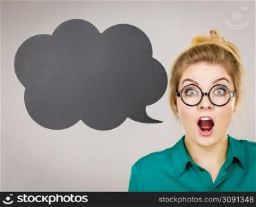 Shocked astonished business woman wearing green shirt with black thinking or speech bubble.. Shocked business woman with thinking bubble
