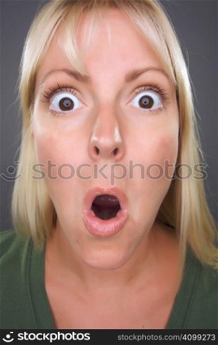 Shocked Blond Woman with Funny Face against a Grey Background