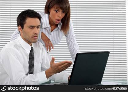 Shocked business couple in front of laptop