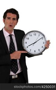 Shocked businessman holding clock