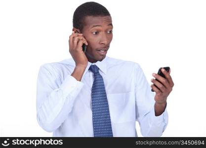 Shocked businessman holding two telephones