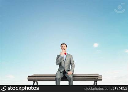 Shocked businessman. Young shocked businessman sitting on wooden bench