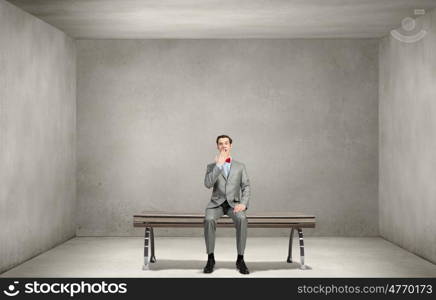 Shocked businessman. Young shocked businessman sitting on wooden bench