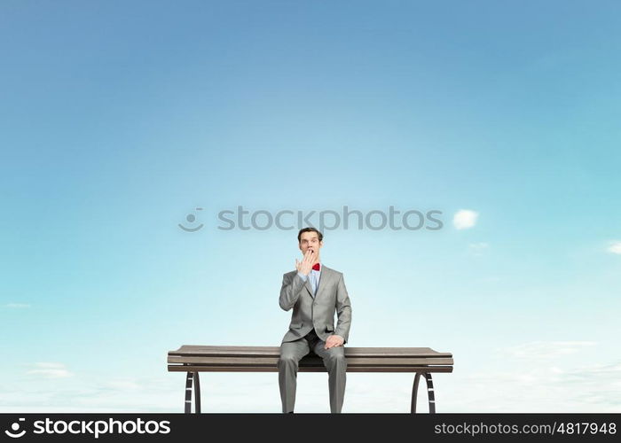 Shocked businessman. Young shocked businessman sitting on wooden bench