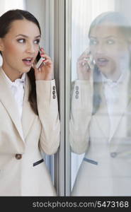 Shocked businesswoman using cell phone in office