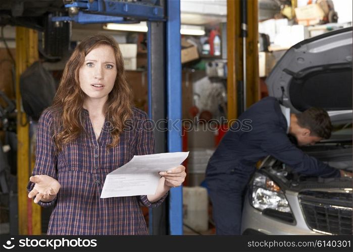 Shocked Female Customer Looking At Garage Bill