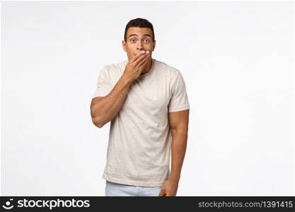 Shocked hispanic young masculine man in t-shirt, gasping cover mouth and stare amazed, speechless, hear unbelievable rumor, gossiping and standing astonished, losing speech from shook.. Shocked hispanic young masculine man in t-shirt, gasping cover mouth and stare amazed, speechless, hear unbelievable rumor, gossiping and standing astonished, losing speech from shook