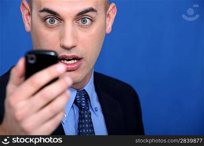 Shocked man looking at mobile telephone