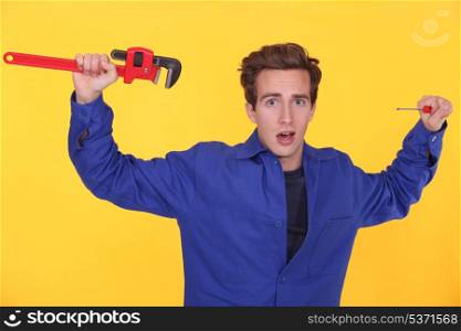 Shocked man stood with wrench and screwdriver