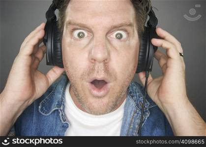 Shocked Man Wearing Headphones against a grey background.
