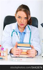 Shocked medical doctor woman sitting at office table with pile of books&#xA;