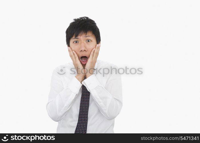 Shocked mid adult businessman with hands on face over white background