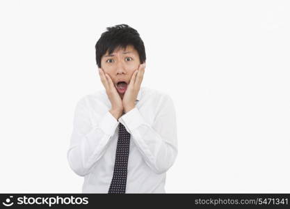 Shocked mid adult businessman with hands on face over white background