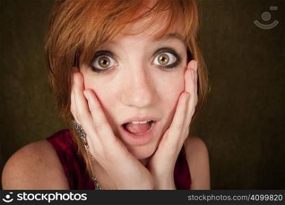 Shocked pretty young girl with red hair on a green background