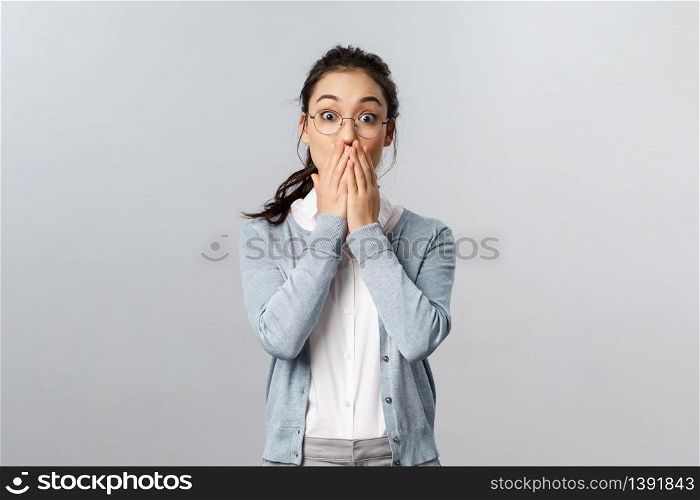 Shocked, speechless attractive asian woman gasping and cover mouth in awe, standing startled over grey background, listening to big shocking news, react impressed at gossip.. Shocked, speechless attractive asian woman gasping and cover mouth in awe, standing startled over grey background, listening to big shocking news, react impressed at gossip