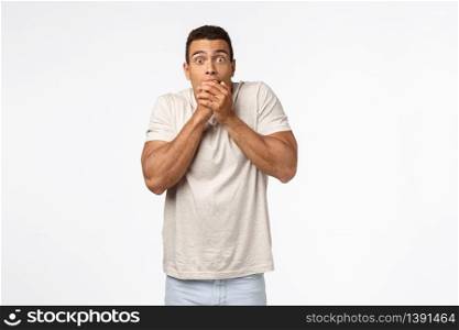 Shocked speechless young hispanic man in t-shirt, gasping amazed, popping eyes from shook and astonishment, cover mouth not scream, heard stunning rumor, standing white background impressed.. Shocked speechless young hispanic man in t-shirt, gasping amazed, popping eyes from shook and astonishment, cover mouth not scream, heard stunning rumor, standing white background impressed