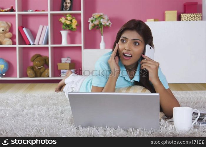 Shocked woman answering mobile phone at home