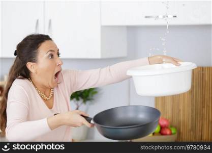 shocked woman calling collecting water leaking from ceiling