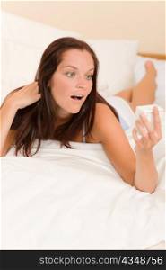 Shocked woman wake-up in white bedroom watch alarm clock