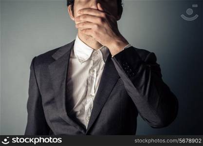 Shocked young businessman covering is mouth
