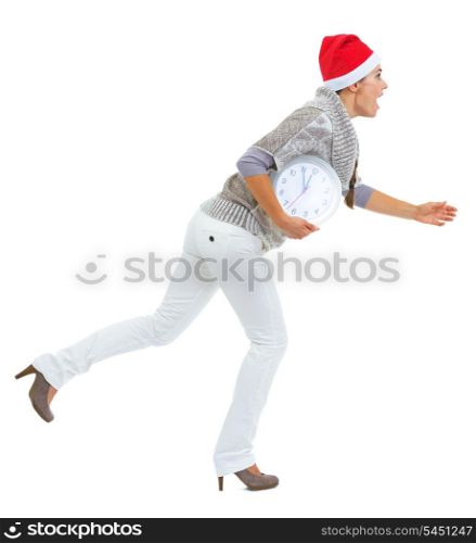 Shocked young woman in sweater and christmas hat running with clock