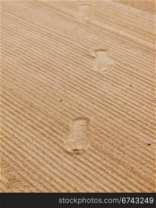 Shoe footprints in rippled sand on beach