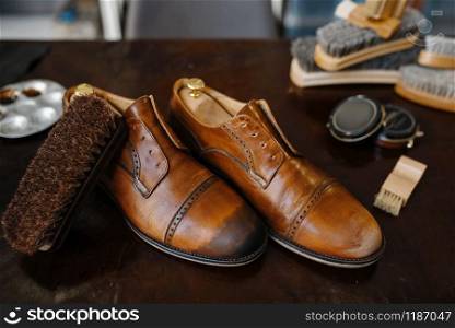 Shoe repair service concept, boots and polish, shoemaker workplace, nobody. Shoemaking workshop, repaired footwear on the table, cobbler job. Shoe repair service concept, boots and polish