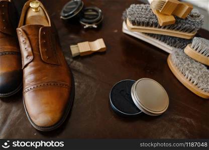 Shoe repair service concept, boots and polish, shoemaker workplace, nobody. Shoemaking workshop, repaired footwear on the table, cobbler job