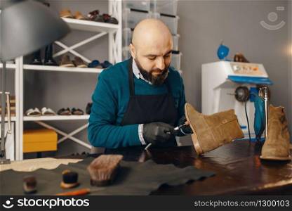 Shoemaker fix the shoe, footwear repair service. Craftsman skill, shoemaking workshop, master works with boots, cobbler job. Shoemaker fix the shoe, footwear repair service