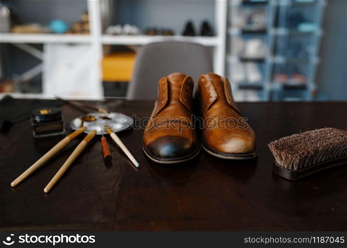 Shoemaker job, footwear repair service concept. Shoemaking workshop, repaired boots and bootmaker tools on the table, cobbler job. Shoemaker job, footwear repair service concept
