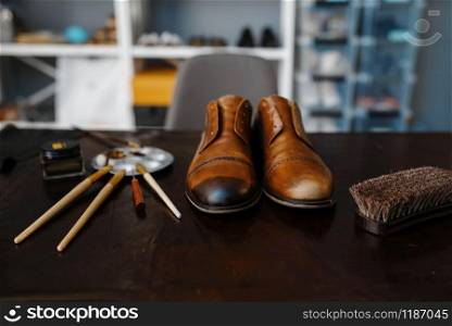 Shoemaker job, footwear repair service concept. Shoemaking workshop, repaired boots and bootmaker tools on the table, cobbler job. Shoemaker job, footwear repair service concept