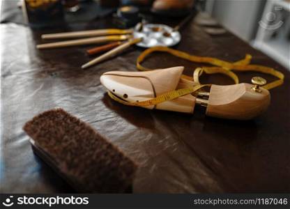 Shoemaker occupation, footwear repair service concept. Shoemaking workshop, repaired boots and bootmaker tools on the table, cobbler job