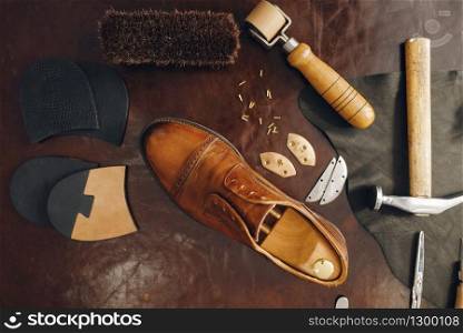 Shoemaker occupation, footwear repair service equipment. Shoemaking workshop, repaired boots and bootmaker tools on the table, cobbler job. Shoemaker occupation, footwear repair equipment