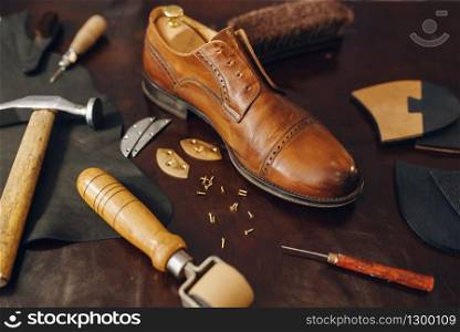 Shoemaker occupation, footwear repair service equipment. Shoemaking workshop, repaired boots and bootmaker tools on the table, cobbler job