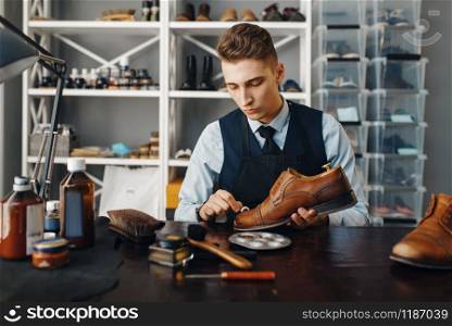 Shoemaker polishes the shoe, footwear repair service. Craftsman skill, shoemaking workshop, master works with boots, cobbler. Shoemaker polishes the shoe, footwear repair