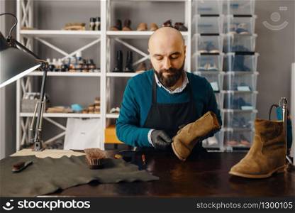 Shoemaker sharpens the shoe sole, footwear repair service. Craftsman skill, shoemaking workshop, cobbler job. Shoemaker sharpens the shoe sole, footwear repair