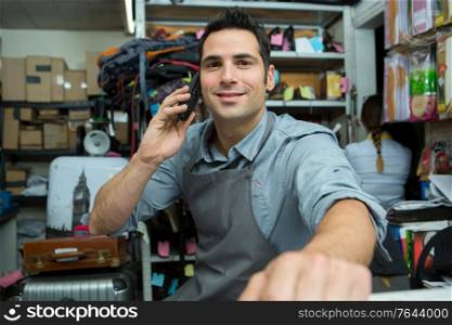shoemaker talking on mobile phone in workshop