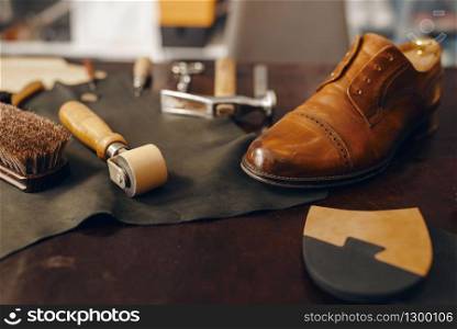 Shoemaker workplace, footwear repair service. Shoemaking workshop, repaired boots and bootmaker tools on the table, cobbler job