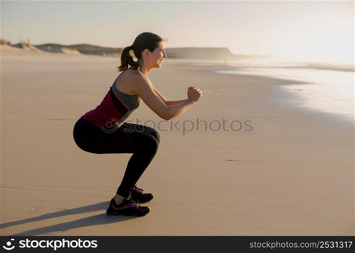 Shoot of a beautiful woman making squats exercises in the beach
