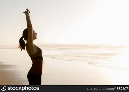 Shoot of a beautiful woman making stretching exercises in the beach