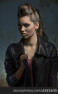 shoot of young fashion girl with wavy brunette hair-style posing with leather jacket in dark atmosphere