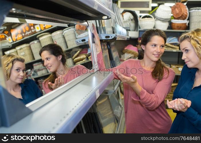 shop assistant helping customer to choose mirror