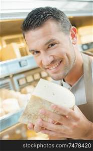 Shop assistant holding chunk of cheese